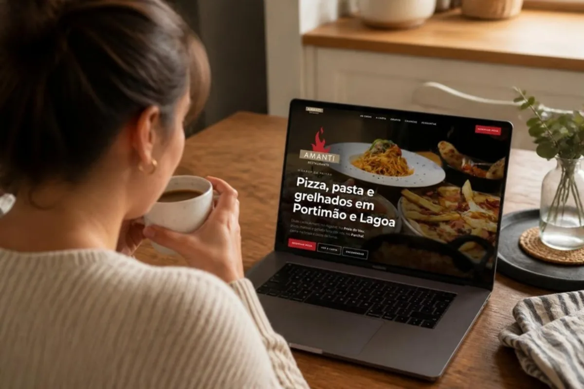 Cliente em casa, à mesa da cozinha, a ver o site do Amanti no portátil e no telemóvel.